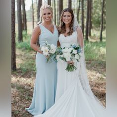 two beautiful women standing next to each other in the woods