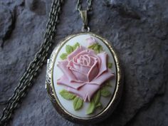 "Beautiful cameo locket. The cameo is a gorgeous pink colored rose with green leaves on a cream background The lockets are bronze or silver plated (antique silver, gold and rose gold are also available, just message me). Victorian style with beautiful etching on the front and back, about 2\" long, please see the photos. It can hold two photos, keepsakes, or even your daily medication or vitamins. Pass down from generation to generation. The chain is a matching 22\" 1.2mm .925 plated snake chain Oval Rose Design Jewelry For Wedding, Vintage Rose-colored Jewelry For Weddings, Vintage Rose Wedding Jewelry, Rose Detail Jewelry For Wedding, Pink Cameo Jewelry For Wedding, Vintage Rose Jewelry For Wedding, Pink Cameo Wedding Jewelry, Rose Jewelry For Wedding And Mother's Day, Pink Rose Design Jewelry For Wedding