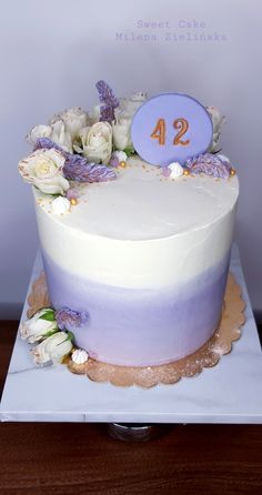 a white cake with purple frosting and flowers on top that reads 42 sweet cakes