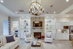 a living room filled with furniture and a fire place under a chandelier in front of a fireplace