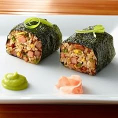 two sushi rolls on a white plate with green sauce