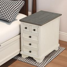 a white bed with a black and white checkered pillow next to it on a wooden floor