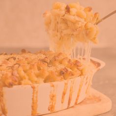 a person scooping macaroni and cheese out of a casserole dish