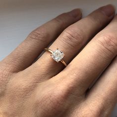 a woman's hand with a diamond ring on top of her finger, showing the center stone