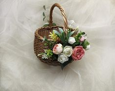 a basket filled with flowers sitting on top of a white bedding covered floor next to a wall