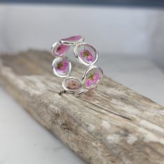 Flowers silver ring meticulously crafted using hand picked flowers and fully cured UV resin. The sterling silver handmade band is inspired by the graceful charm of Boho jewelry. This pink ring gift is a perfect meaningful gift for a beloved woman, and as a pampering gift for yourself. The jewelry is very flattering, lightweight, comfortable to wear as jewelry for everyday use and impressive as jewelry for a special occasion. Each piece is individually crafted to order, ensuring a unique touch, with subtle variations that make every piece truly one-of-a-kind. Elevate your style with this exceptional jewelry- a wearable piece of art designed for your enjoyment. Purchase now for an exquisite blend of nature and craftsmanship. Special Features: - Handmade with Natural pink Lobularia flowers, f Pink Flower Shaped Sterling Silver Ring, Pink Flower Sterling Silver Ring, Pink Flower-shaped Sterling Silver Ring, Sterling Silver Flower Ring In Pink, Pink Sterling Silver Flower Ring For Gift, Handmade Sterling Silver Petal Jewelry, Pink Sterling Silver Flower Ring As Gift, Delicate Silver Flower Ring, Sterling Silver Flower Jewelry With Pressed Flowers