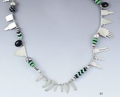 Presented is a sterling silver and glass bead necklace by jewelry artist Roberta Williamson. The necklace is signed and dated 1987. The artist is known for making quirky, individualistic jewelry art using estate sale or otherwise 'found' materials, as well as stylized silver castwork of her own design. Every piece of hers is unique and one-of-a-kind, though her personal style remains distinct. This necklace consists of green and black glass beads in a variety of styles, interspersed with stylize Artsy Silver Necklace With Unique Variations, Modern Silver Beaded Necklace, Unique Silver Beaded Necklaces With Spacer Beads, Unique Sterling Silver Beaded Necklaces, Artistic Silver Jewelry With Round Beads, Modern Beaded Necklaces, Fish Pendant Necklace, Silver Beaded Necklace, Jewelry Artist