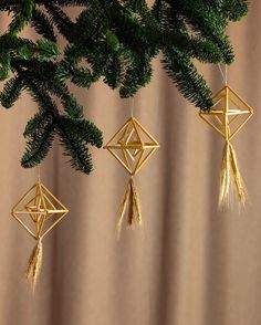 three gold ornaments hanging from a tree branch