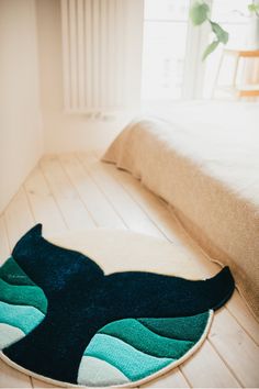 a blue and green rug on the floor next to a bed in a room with white walls