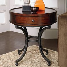 a table with a phone and an orange vase on it in front of a couch