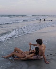 two people are sitting on the beach together