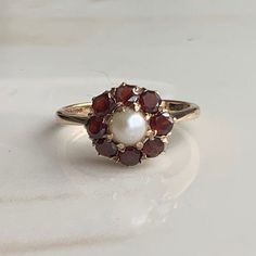 A vintage 9 carat gold Garnet and Pearl cluster ring.  CONDITION: Wear consistent with age and use. Please see photos for more detail. Stones all in good condition. HALLMARKED 9 CARAT GOLD, ASSAYED IN LONDON 1957 SETTING DIAMETER: 10mm  GARNET SIZE: 3mm (0.10 carats) PEARL SIZE: 4mm (0.33 carats) BAND WIDTH NARROWEST: 1.5mm RING SIZE: UK: J | US: 4 3/4 WEIGHT: 2.3 grams (SZ) 50s Wedding Ring, Garnet And Pearl Ring, Vintage Rings Antiques, Elizabeth Taylor Ring, Pearl Engagement Ring Vintage, Garnet And Pearl, Wedding Ring Antique, Pearl Cluster Ring, Pearl Rings Vintage