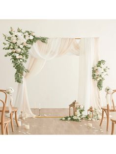 a wedding arch decorated with white flowers and greenery