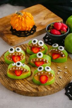 green monster cookies with strawberries and oranges on a wooden board next to pumpkins