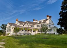 a large white house sitting in the middle of a lush green field with steps leading up to it