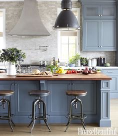 a kitchen with blue cabinets and stools next to an island in front of the stove