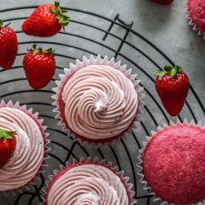 cupcakes with pink frosting and strawberries on a cooling rack, top view