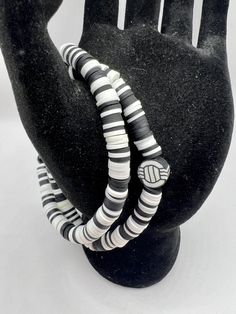 a black and white striped bracelet on top of a mannequin's hand