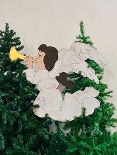 a paper cut out of an angel on top of a christmas tree with a trumpet