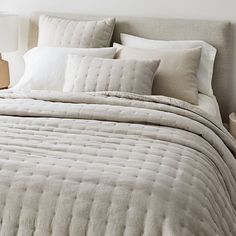 the bed is made with white linens and pillows, along with two nightstands