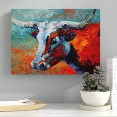 a painting of a cow on a wall next to a potted plant and books