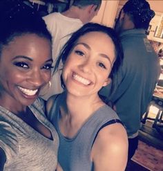 two women are smiling for the camera in a restaurant or bar, one is holding her arm around the other's shoulder