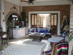 a living room filled with lots of furniture next to a brick wall and ceiling fan