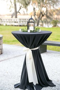 a black and white table with a lantern on it's top, tied to the side