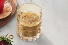 a glass filled with liquid sitting on top of a counter next to a plate and utensils