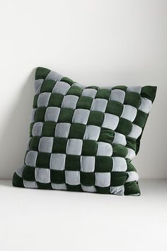 a green and white checkered pillow sitting on top of a bed next to a wall