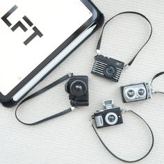 four cameras sitting on top of a table next to an electronic device with the letter f in it