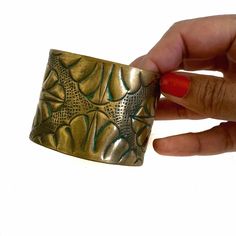 This vintage handmade 1970s cuff bracelet was sourced in Mexico City! It is lightweight and adjustable. The cuff is made of a gold-toned brass, and is hammered and embossed with an abstract floral/leafy pattern. The edges of the details have a lovely blue patina. In very good condition, although due to age and past adjustments, the cuff is not a perfect circle/oval.  The circumference of the cuff is about 8 inches. The part that sits visible on top of your wrist is 1.75 inches  Label: no label. Vintage, handmade Material: Brass Condition: Good/Very good  P lease note: I do not accept returns so please make sure to take measurements into account to ensure sizing accuracy, as well as carefully reading the item descriptions. Feel free to contact me with any questions prior to purchasing. All Vintage Adjustable Brass Bangle, Adjustable Vintage Brass Bangle, Vintage Gold Brass Cuff Bracelet, Handmade Brass Cuff Bracelet Collectible, Antique Gold Brass Cuff Bangle Bracelet, Vintage Antique Gold Brass Cuff Bracelet, Bronze Brass Cuff Bracelet, Handmade Brass Cuff Bracelet, Vintage Hand Cast Bangle Cuff Bracelet