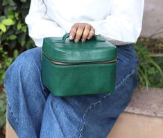 a person sitting on a bench holding a green case