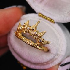 a close up of a gold ring in a box with a white cloth around it