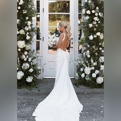 a woman standing in front of a white door with flowers on the wall behind her