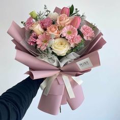 a person holding a bouquet of pink and white flowers in their hand with the tag on it