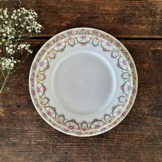 an empty plate on a wooden table next to some baby's breathflowers