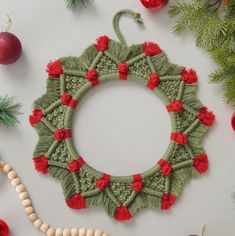 an ornament made out of yarn and beads on a table with christmas decorations