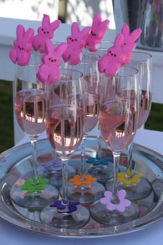 some wine glasses with pink peeps on them are sitting on a silver platter