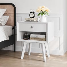 a white bedside table with flowers and books on it