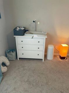 a baby crib in the corner of a room next to a night stand and lamp