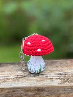 a red and white mushroom keychain sitting on top of a wooden table