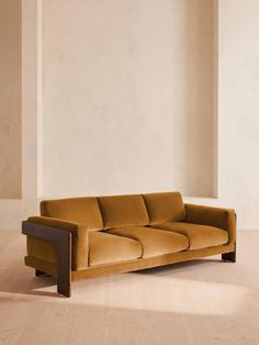 a brown couch sitting on top of a hard wood floor next to a white wall