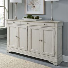 a white buffet table with two lamps on top