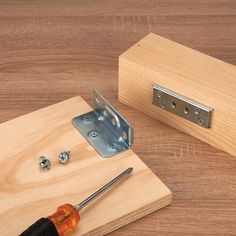 a screwdriver is sitting on top of a piece of wood next to a door hinge