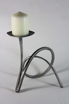 a white candle sitting on top of a metal stand