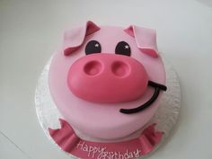 a pink birthday cake with a pig face on it