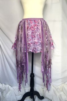 This is a handmade, ooak, unique floral skirt.  Has an elastic waistband, and multiple shades of purples and pinks that make up the fringe.  Many hours of hand sewing went into making this little gem.   She will best fit waist/hips from 32 to 35 inches. The skirt measures 14~141/2 inches long without the dangling materials. If you include the dangles, she measures roughly 32 inches long.  I am a size medium and it fits me perfectly ;)  She is ready and waiting to be shipped out, worn and loved today!  Any questions? Just ask ;)  Thanks so much for looking Fairy Grunge Mini Skirt For Festival, Fairy Grunge Skirt For Spring, Bohemian Flowy Mini Skirt For Festival, Bohemian Fringe Mini Skirt For Summer, Pink Mini Skirt For Spring Festival, Pink Fitted Bohemian Mini Skirt, Bohemian Mini Skirt For Spring Festival, Spring Festival Bohemian Mini Skirt, Spring Bohemian Mini Skirt