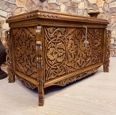 an intricately carved wooden chest sitting in front of a stone wall