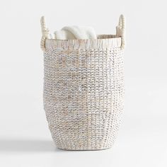 a white basket with two handles and some towels in the bottom one is made out of woven material